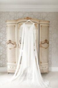 Wedding gown hung up in front of mirror