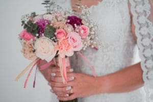 Image describes a bride holding a wedding bouquet.
