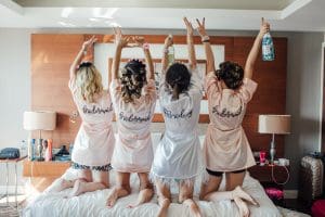 Bride and bridesmaids on a bed in a hotel room
