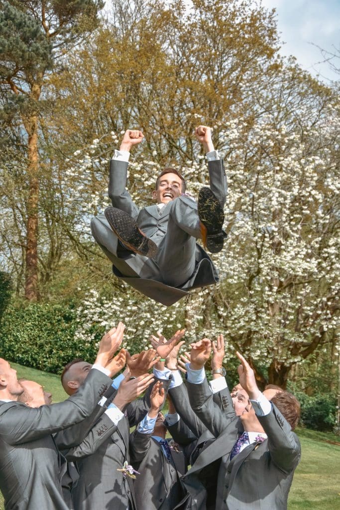 Groom getting thrown up in the air.